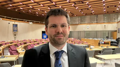 A head and shoulders picture of Councillor James Courtenay inside the Southend Council chamber