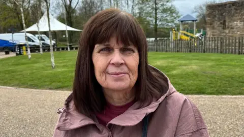 Charlie Stubbs / BBC There is a woman in her 50s with a pink coat and a dark pink t-shirt underneath. She has brown shoulder-length hair and a fringe that covers her forehead.