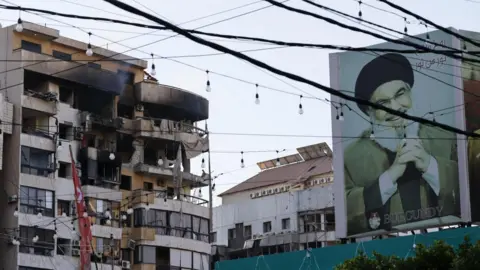EPA A billboard with a photo of the late Hezbollah leader Hassan Nasrallah is seen near a damaged building following an Israeli airstrike in the southern Beirut suburb of Haret Hreik, Lebanon (02 March 2026)