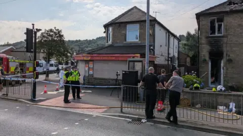 BBC/David Spereall Investigations continue at the scene of the blaze in Huddersfield