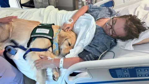 PA Real Life Charlie Vincent in a hospital bed with his hand on a dog