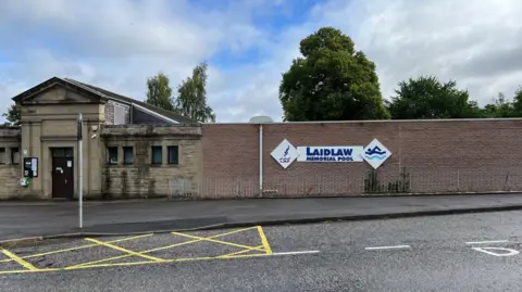 A long narrow building with a road in front
