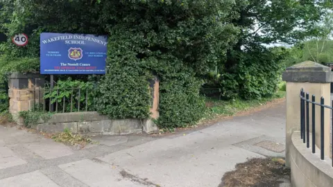 Alex Moss/BBC A blue sign outside a driveway which says 'Wakefield Independent School'.