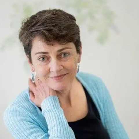 Annie Barrows Annie Barrows wearing a light blue cardigan, short hair and earrings.