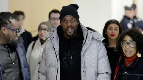 Reuters Mathias Pogba, brother of Paul Pogba, arrives at court in Paris with crowd of people around him