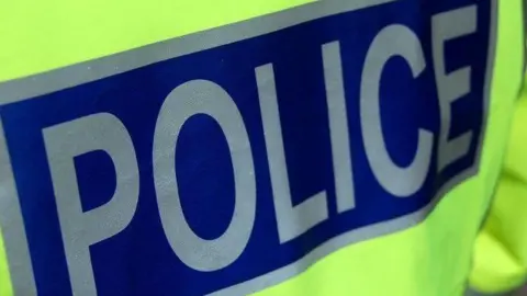A close up of a police officer's jacket with the word "police" in silver letters on a dark blue background.