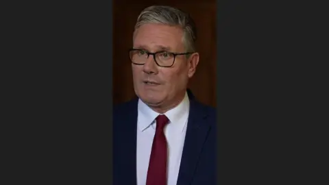 Starmer in a red tie and blue suit.