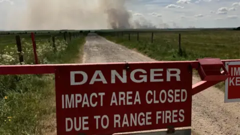A red sign on Salisbury Plain's military training area starting "DANGER, IMPACT AREA CLOSED DUE TO RANGE FIRES".