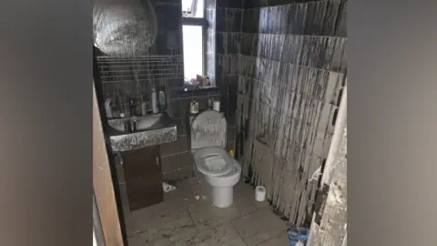 Family handout The bathroom with smoke and fire damage. The toilet is covered in soot as are the walls.