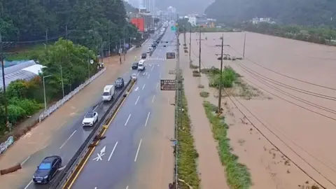 Cars pass through a severely flooded highway in Geoje, Gyeongsang, South Korea