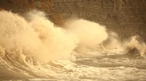 Large waves break against Church Cliff Walkway, East Cliffs, Lyme Regis