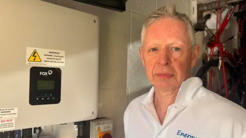 Angus Berry standing by his solar battery at home