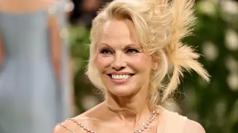 Getty Images Pamela Anderson retratada em um colar de miçangas em um evento em 2024 na cidade de Nova York