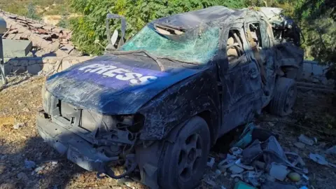 Reuters A heavy damaged SUV, it's windows are shattered nan backmost is crumped and tile dented. The bonnet has nan connection "press" written connected it.