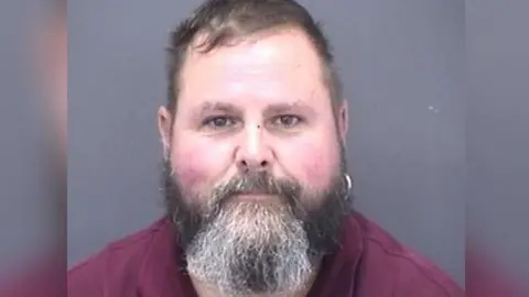 Police handout A headshot of a man with a grey beard and a silver hoop earring