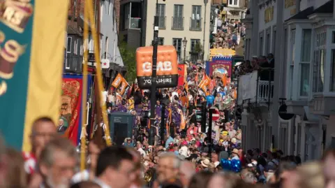 A view up the high street in Durham. The street is packed with hundreds of people.