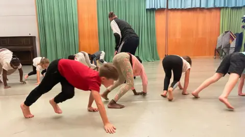 Simon Thake Children, dressed in casual clothes, move on all-fours around a dance studio
