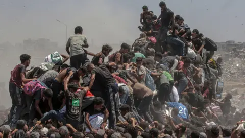 EPA Crowds of Palestinians swarm an aid truck as they try to grab bags of flour.