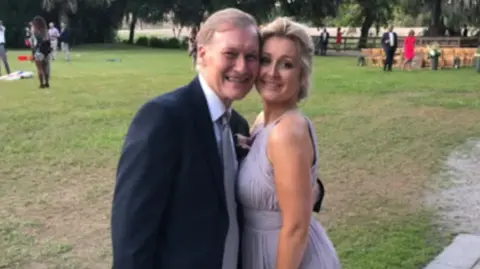 A father and daughter in formal dress hug each other for the camera