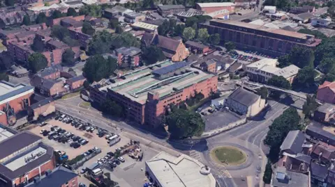 Aerial view of a multi-storey car park with a small area covered by a canopy carrying solar panels.