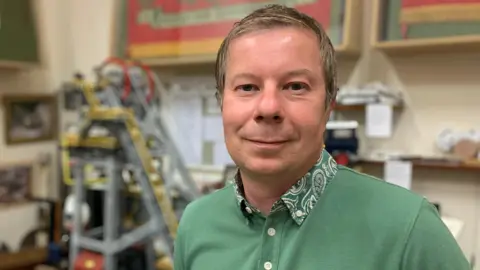 BBC Former miner standing with mining memorabilia behind him.