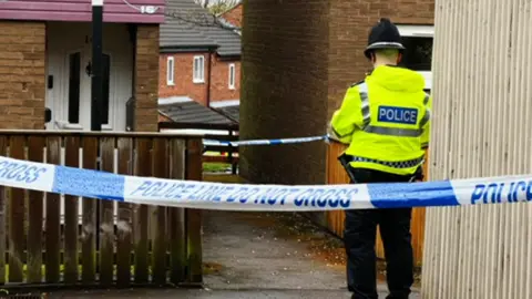 Police officer standing between police tape