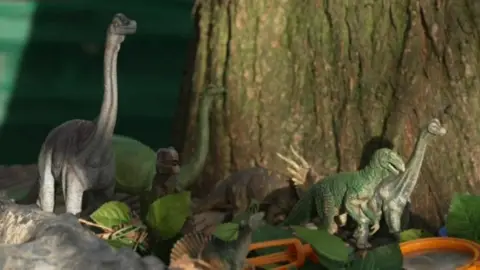 Toy dinosaurs in a woodland play area