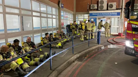 Firefighters congregated outside the entrance to the hospital after the fire was tackled
