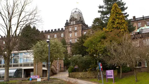 External view of Derbyshire County Council's ornate Victorian headquarters, seen through a screen of trees