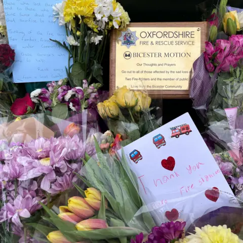 Bunches of flowers, with plaque and cards among them.