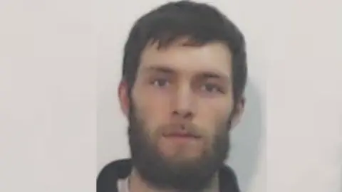 Police Scotland A mugshot of a man with dark hair and a dark beard