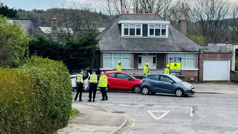 BBC Emergency services at the scene of a crash, one white car is on its roof.