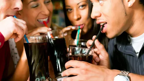 Getty Images Four friends drinking soda in a bar with colorful straws