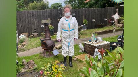 Woman in protective suit and wellies in her garden