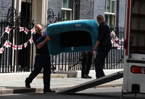 EPA-EFE/REX/Shutterstock Two men carry a turquoise sofa into a van outside Downing Street