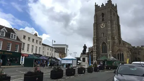 Local Democracy Reporting Service Market Hill in Sudbury, with the church and market stalls in view