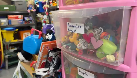 A pink drawer full of multicoloured toys that have been donated to a baby bank. 