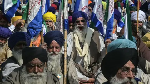 Getty Images A group of Sikh farmers wearing turbans and shawls, and holding flags, stage a protest against the US-India interim trade agreement in Punjab. 