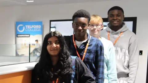 From left to right, Aileen Jomon, Calix Alemonai, Dawid Sciborowski and Jesse Abdul Karim at the new college campus in Telford. The four students wear casual clothes and have orange lanyards around their next with a sign saying "Telford College" behind them