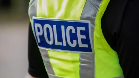 A stock image of a police officer wearing a hi-vis jacket with the word "Police" on the back.