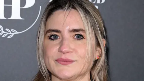 Jeff Spicer/Getty Images The head of Kemsley, a woman with brown and lighter hair, goes from top to bottom in the centre of the image. A grey background is behind her.