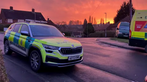 An ambulance rapid response car parked on a road at sunset.