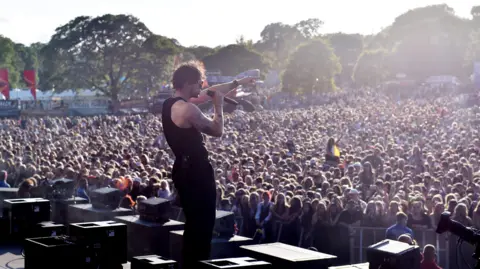 Tom Grennan sings to the crowd at Camperdown Park in Dundee - a sea of faces stretching back to the tree line.