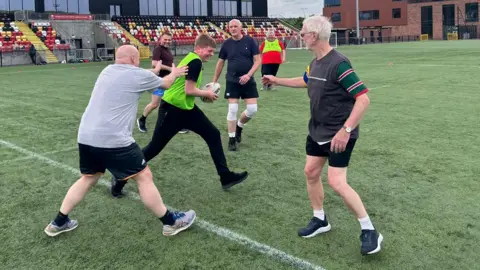 Supplied A group of men of different ages playing rugby on a 4g pitch.