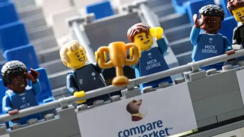 Peterborough United Lego Peterborough United players holding a trophy aloft in the replica stand