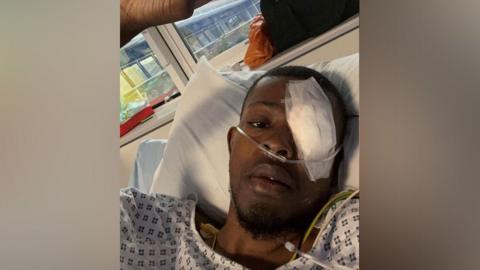 Farid Oladapo in hospital bed with eye patch