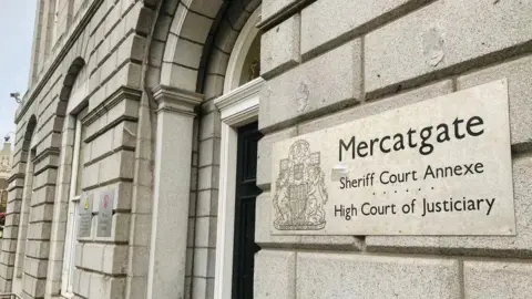 BBC Grey granite building with a black door, and a sign saying 'High Court of Justiciary'