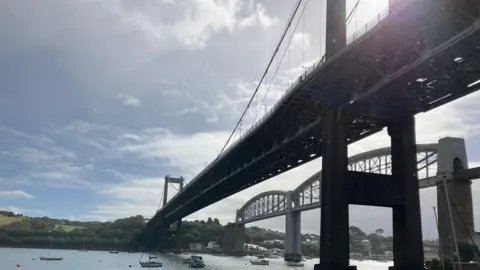 Two bridges are in this shot over the River Tamar. The A38 road bridge is to the left of the Royal Albert Bridge designed for the railways by Isambard Kingdom Brunel which opened in 1859.
Small boats are on the river below.