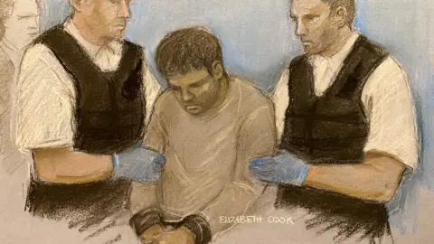 PA Media Courts Dawood Safi, dressed in a grey jumper, being led into court at Westminster Magistrates' Court by two policemen, in London in October 2025.
