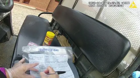 Lincolnshire Police A still from body-worn police footage. A person wearing clear plastic gloves is writing on to an evidence bag. A yellow tub can be seen behind it. An evidence bag and yellow pot are placed on a black seat in a vehicle.